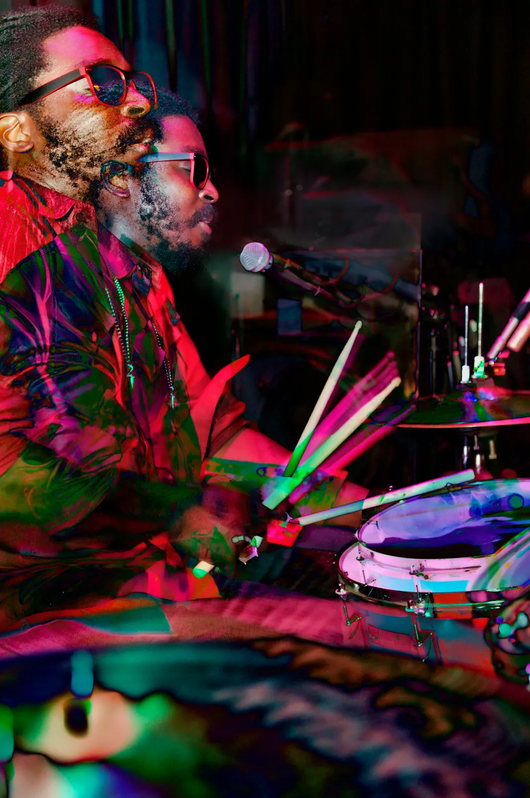 Jubba White performing live on drums under colorful stage lighting